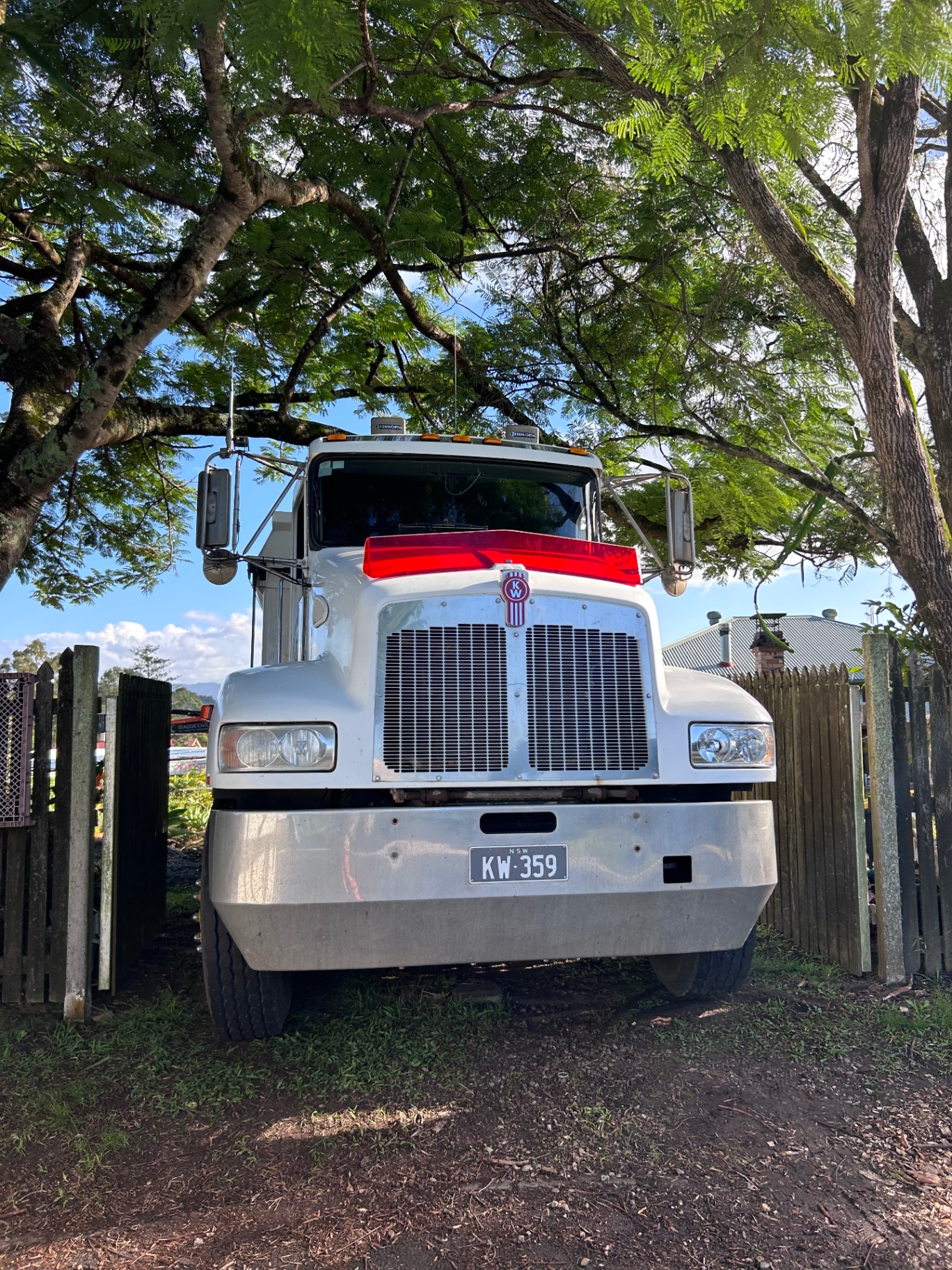 Front view of Byron Bay Tippers work truck parked on site beneath large trees